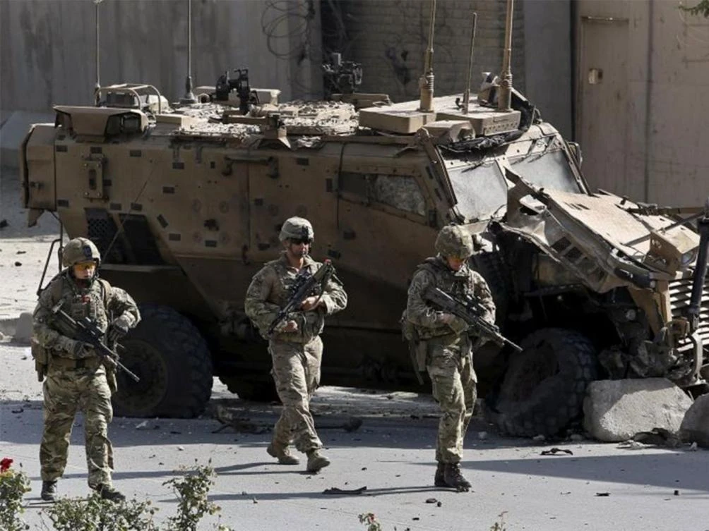 Nato soldiers walk in front of a damaged Nato military vehicle at the site of a suicide car bomb blast in Kabul. (Reuters)