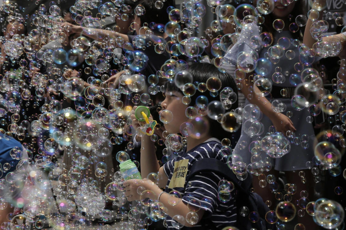 A boy plays with bubbles during an art display titled "Bubble Up" created by Japanese artist Shinji Ohmaki in Hong Kong, Wednesday, Aug. 2, 2017. (AP)