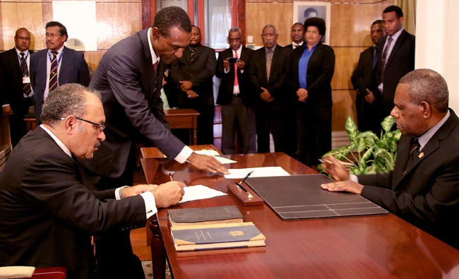 This handout photo taken and received on Wednesday shows Papua New Guinea Prime Minister Peter O'Neill (L) signing his oath of office before Governor-General Bob Dadae (R) in Port Moresby. (AFP)