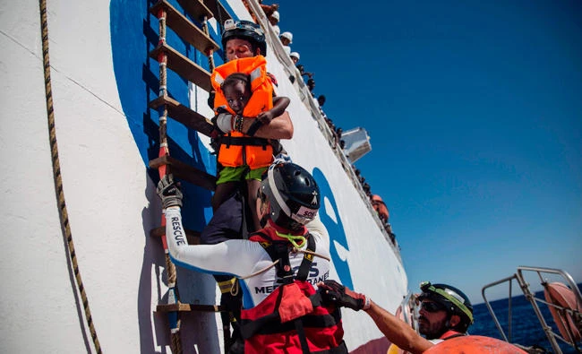 A rescue worker helps a migrant girl in the Mediterranean Sea, 20 nautic miles from the Libyan coast, on Tuesday. (AFP)