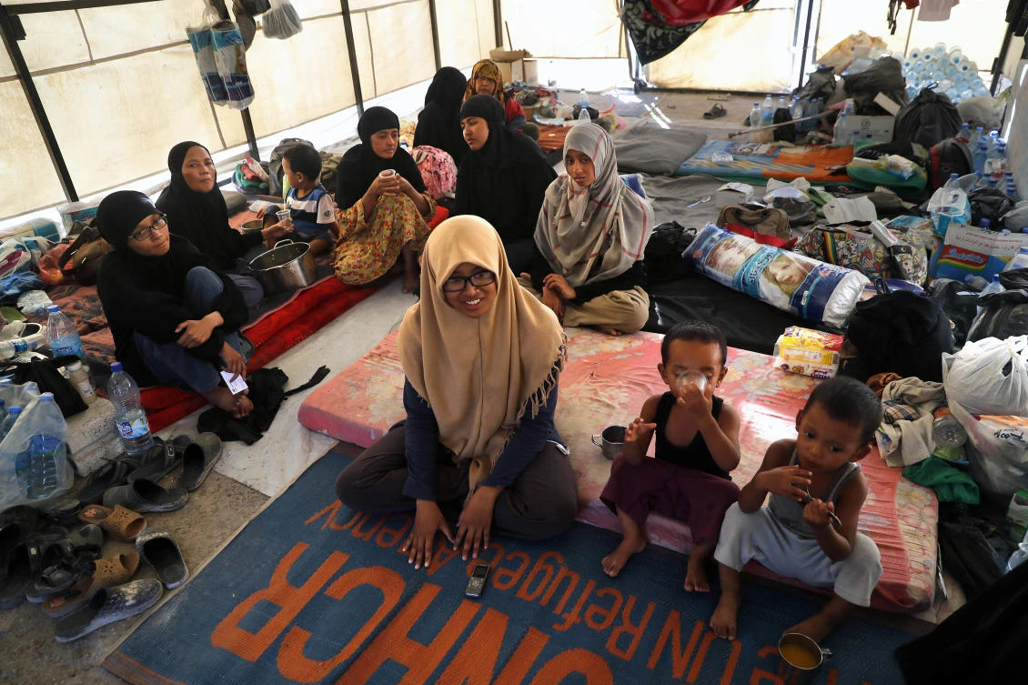 In this picture taken on Monday, July 24, 2017, an Indonesian family who escaped from the Islamic State group in Raqqa gather inside their tent at a refugee camp, in Ain Issa, Syria. The family is among thousands from Asia, Europe, Africa, North America and the Middle East who chased the dream of a new Islamic society advertised by IS in slickly produced propaganda videos, online blogs and other social media. (AP Photo/Hussein Malla)