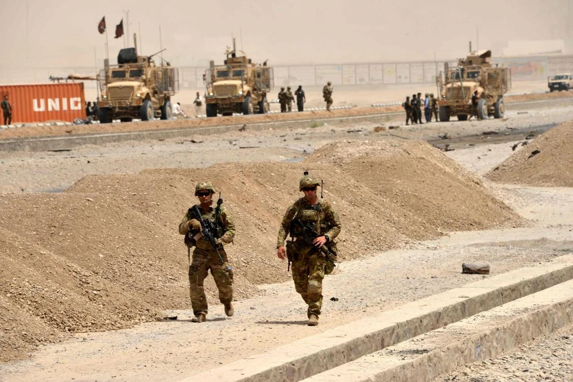 US soldiers walk at the site of a Taliban suicide attack in Kandahar on August 2, 2017. A Taliban suicide bomber on August 2 rammed a vehicle filled with explosives into a convoy of foreign forces in Afghanistan's restive southern province of Kandahar, causing casualties, officials said. "At around noon a car bomb targeted a convoy of foreign forces in the Daman area of Kandahar," provincial police spokesman Zia Durrani told AFP. / AFP / JAVED TANVEER