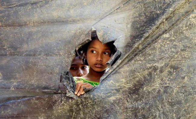 File photo shows a Rohingya refugee girl peeks through a hole made in a plastic wall dividing the shelters at Balu Kali Refugee Camp in Cox's Bazar, Bangladesh. (Reuters)