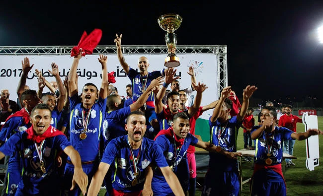 Players of the Gaza-side Shabab Rafah football team celebrate with the Palestinian cup following their victory in the second leg of the Palestinian Cup final at the stadium in the city of Dura, near the West Bank town of Hebron, on Friday. (AFP / HAZEM BADER)