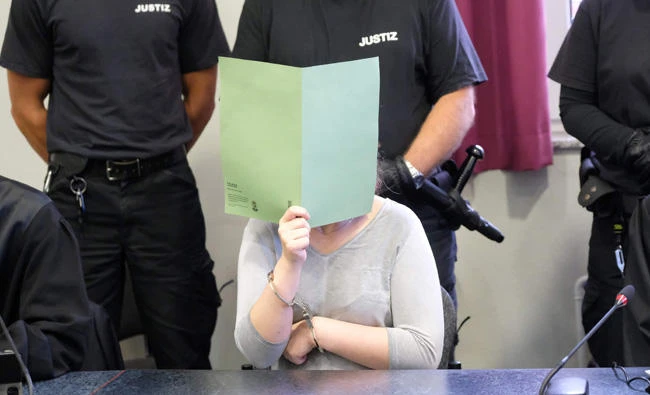 Xenia I covers her face during a verdict reading in a courtroom of the regional court in Dessau Rosslau, Germany, on Friday. (AFP)