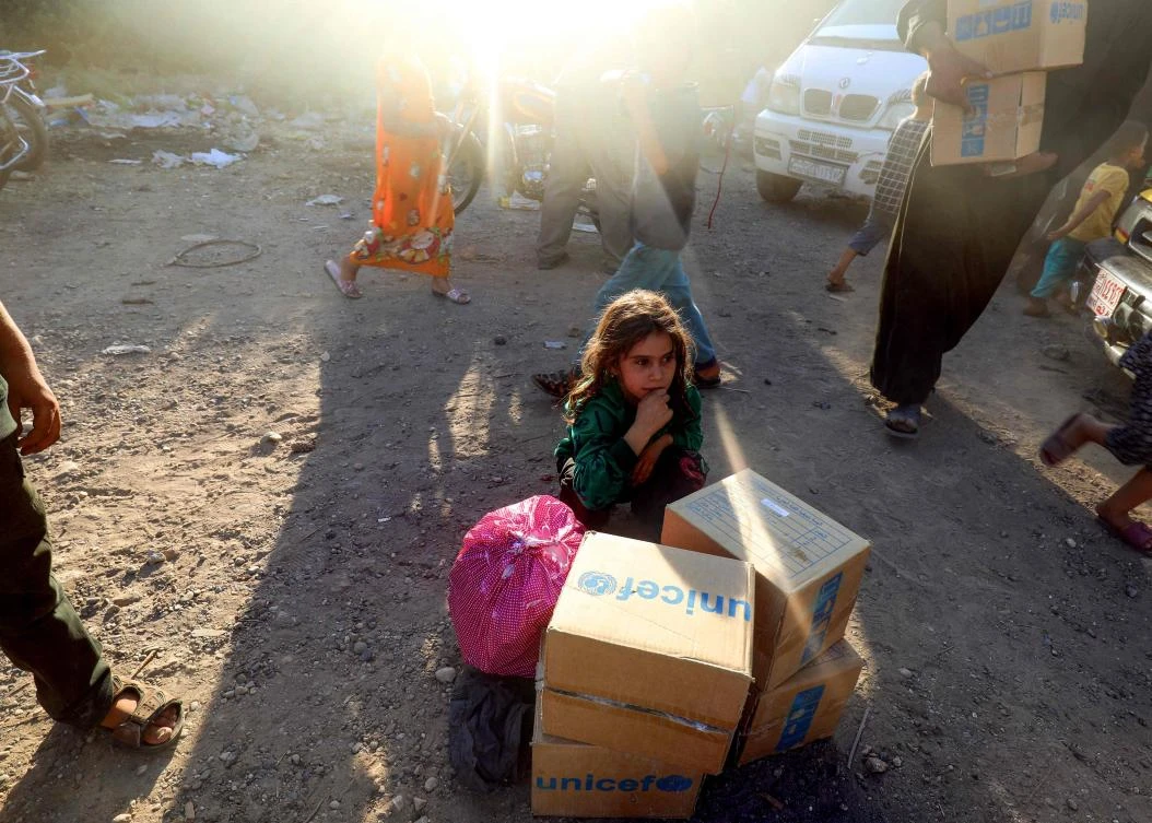 A displaced Syrian child, who fled from Daesh's Syrian stronghold of Raqqa, sitting behind humanitarian aid boxes
delivered by UNICEF at a temporary camp in the town of Tabqa. (AFP)