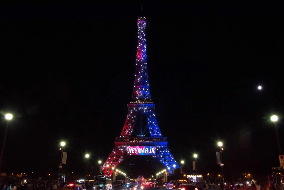 Red and blue lights and a welcoming message that reads in French "Neymar Jr." adorn the Eiffel Tower to celebrate the arrival of Brazilian footballer Neymar to Paris on August 5, 2017 after his signing with the Paris Saint-Germain (PSG) football club. Paris Saint-Germain football club celebrated the arrival of the Brazilian superstar to the French capital following his 222-million-euro ($264m) transfer from Barcelona. / AFP / OLIVIER MORIN