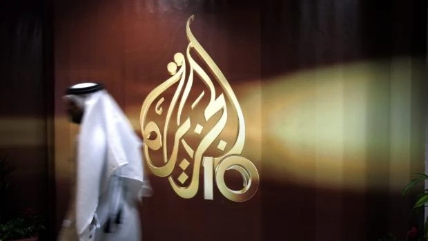 FILE - In this Wednesday Nov. 1, 2006 file photo, a Qatari employee of Al Jazeera Arabic language TV news channel walks past the logo of Al Jazeera in Doha. (AP)