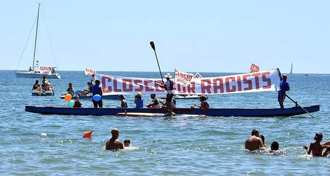 People hold banners and flags as they take protest against the scheduled arrival of the C-Star, a ship that an anti-immigrant group has chartered to try and halt migrant arrivals to Europe, in Catania, Sicily Island, Italy, July 29, 2017. (AP)