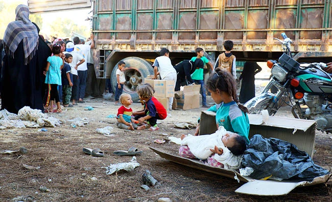 A photo taken on August 4, 2017 shows displaced Syrian children, who fled from Daesh group's Syrian stronghold of Raqqa, receiving humanitarian aid delivered by UNICEF at a temporary camp in the town of Tabqa, about 55 kilometres west of Raqqa. (AFP)