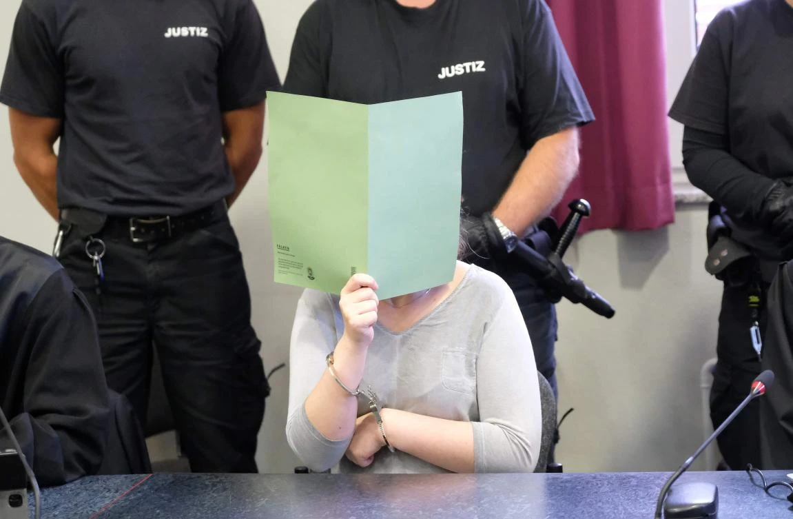 The defendant Xenia I covers her face with a folder during a verdict reading in a courtroom of the regional court in Dessau Rosslau, Germany, on August 4 2017. A German couple received lengthy jail sentences on August 3 for brutally raping and killing a Chinese student in eastern Germany, in a crime that caused outrage in both countries. - Germany OUT / AFP / dpa / Sebastian Willnow