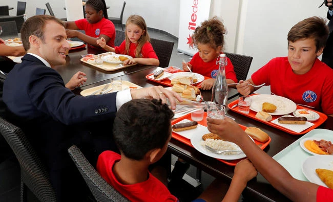 French President Emmanuel Macron shares a lunch with youngsters during his recent visit to a recreational center for children in Moisson. (Reuters)