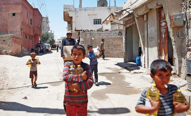Syrian children and a man carry food aid in Douma, near Damascus. (Reuters)