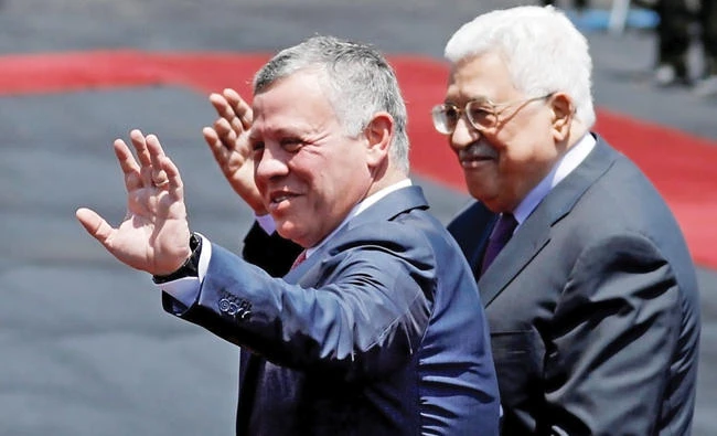 Jordan’s King Abdallah and Palestinian President Mahmoud Abbas wave during a reception ceremony in the West Bank city of Ramallah on Monday. (Reuters)