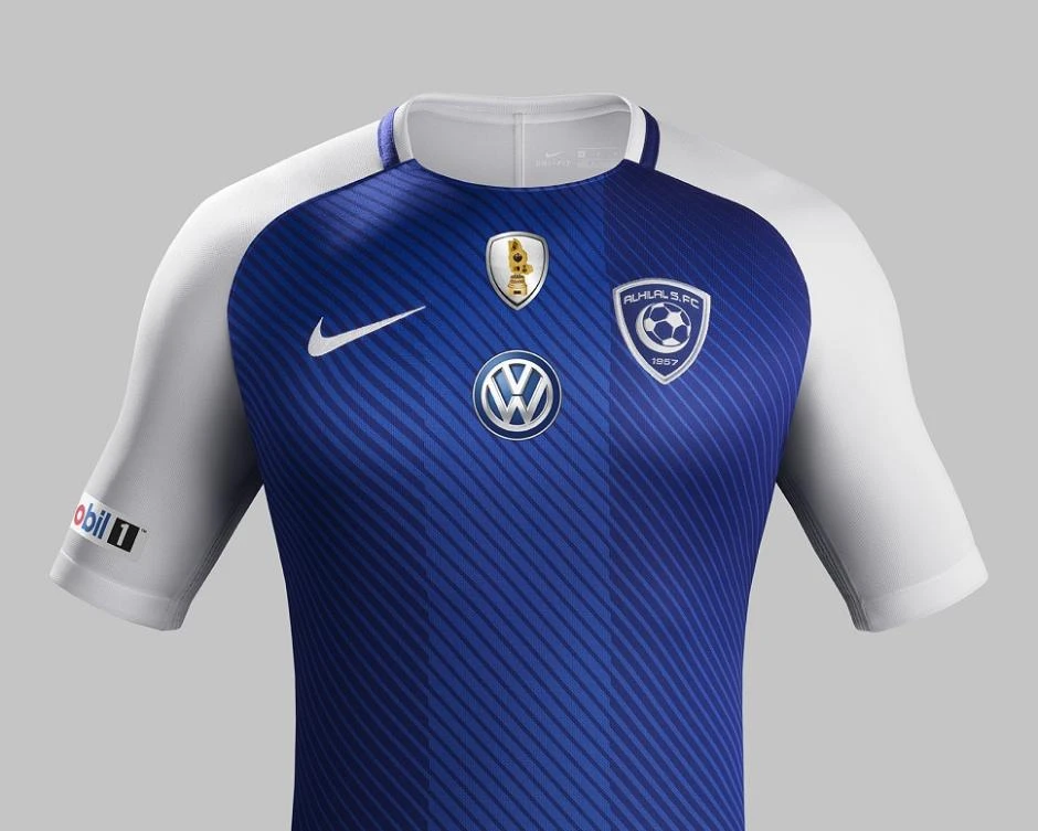 The home shirt features diagonal gradient shades of blue with a darker composition on the frontal sides.
