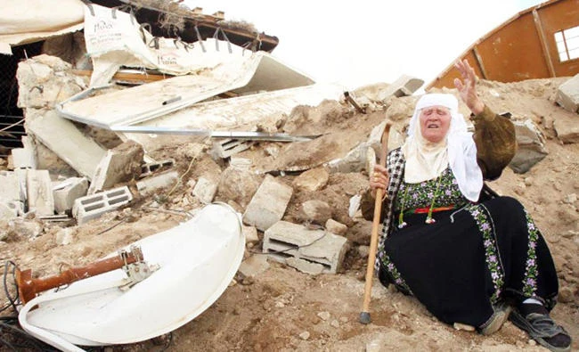 A Palestinian woman sits next to the remains of her home after it was demolished by Israeli bulldozers in Musafir Jenbah, West Bank, in this file photo. (AFP)