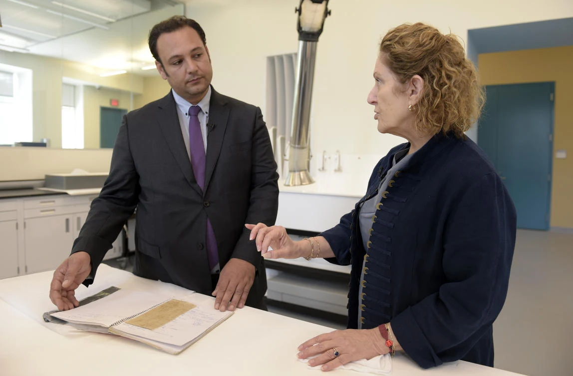 Jane Klinger, right, chief conservator for the United States Holocaust Memorial Museum, talks with Mansour Omari, left, a Syrian human-rights activist documenting cases of people who have disappeared under President Bashar Assad's government, who shows scraps of fabric with the names of fellow inmates he is presenting to the U.S. Holocaust Memorial Museum for preservation at the conservation center, Tuesday, Aug. 8, 2017, in Bowie, Md. (AP Photo/Susan Walsh)