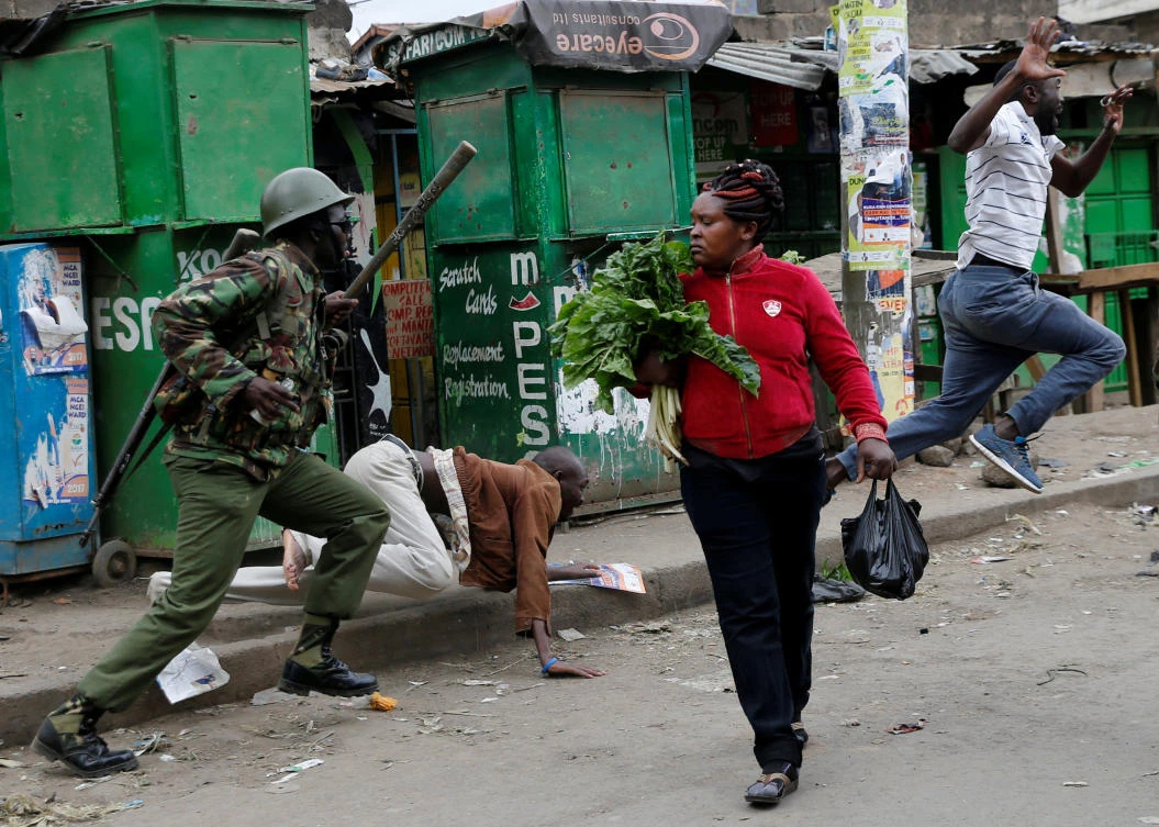 An anti riot policeman attempts to disperse people from the street as a woman carrying vegetables walks past in Mathare, in Nairobi, Kenya August 9, 2017. REUTERS/Thomas Mukoya TPX IMAGES OF THE DAY