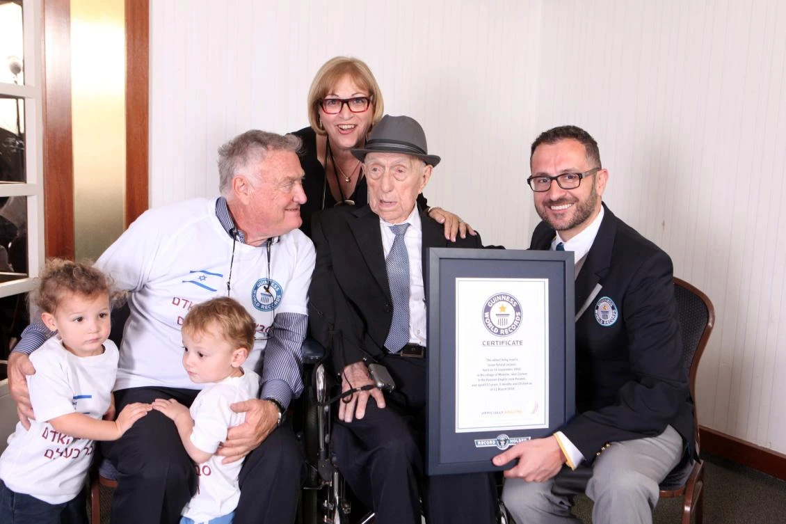 This handout file picture released by Guinness World Records on March 11, 2016 Marco Frigatti (R), head of Records for Guinness World Records, presenting Israel Kristal (2nd-R) with his certificate of achievement for Oldest Living Man, in the presence of the Kristal's daughter (top, son (L) and grandchildren. (AFP / Guinness World Records / Dvir Rosen)