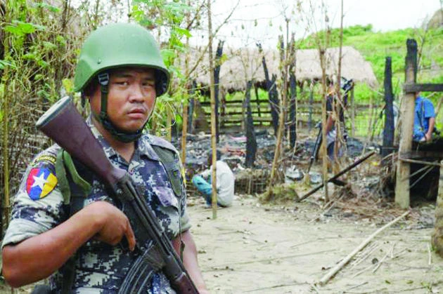 A Myanmar border guard police officer stands guard in front of the remains of a house burned down in a clash between suspected militants and security forces in Tin May village, Buthidaung township, northern Rakhine state, in this July 14 photo. (Reuters)