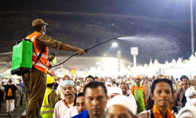 A Saudi security officer sprays water over pilgrims to beat the heat in Makkah. (AP file photo)