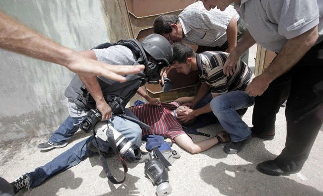 A picture taken on May 31, 2013 shows Palestinian journalist Ashraf Abu Shaweesh being given assistance after being injured by tear gas during clashes following a protest against the expropriation of Palestinian land by Israel in the village of Kfar Qaddum, near the occupied West Bank city of Nablus. The internal Palestinian conflict and the larger Arab-Israeli conflict are taking their toll on journalism in Palestine. (AFP file photo)