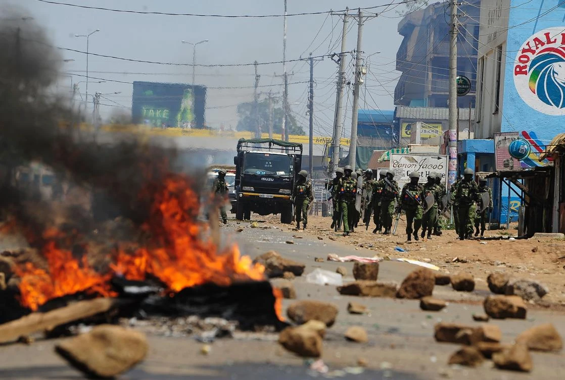 Kenyan security personnel walk towards burning barricades on a road in Kisumu on August 9, 2017, as they clash with National Super Alliance (NASA) supporters after the announcement of national election results. (AFP)
