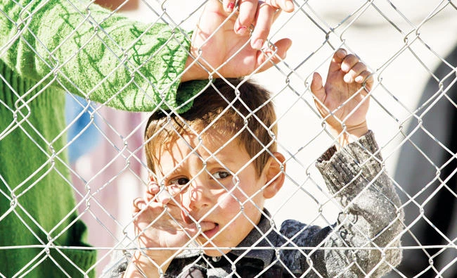A young boy holds onto a fence in Suruc, on the Turkey-Syria border, in this file photo. (AP)