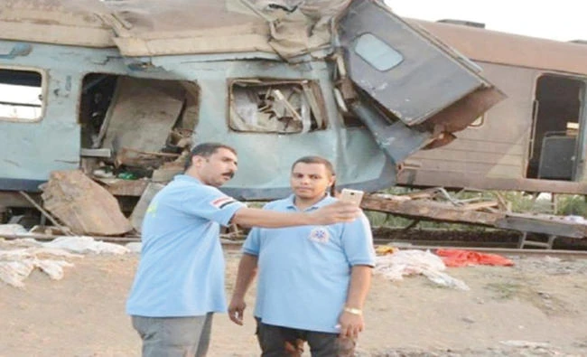 Rescuing personnel take selfies at the side of the train accident near Khorshid station in Alexandria. (Twitter photo)