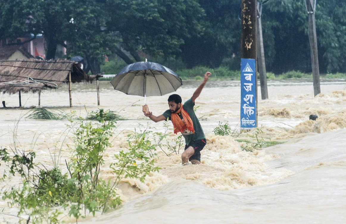 A Nepalese man looses his balance while crossing a flooded street in Birgunj, Nepal, Sunday, Aug. 13, 2017. An official said torrential rain, landslides and flooding have killed dozens of people in Nepal over the past three days, washing away hundreds of homes and damaging roads and bridges across the Himalayan country. (AP)