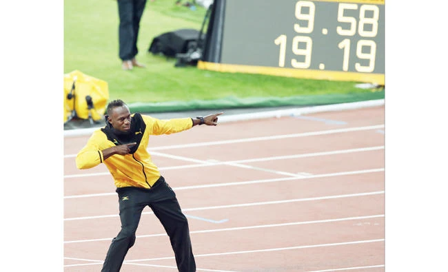 Jamaica’s Usain Bolt performs his trademark pose in front of a screen showing his world record times during a victory lap to mark his athletics career at the end of the World Athletics Championships in London Sunday. (AP)