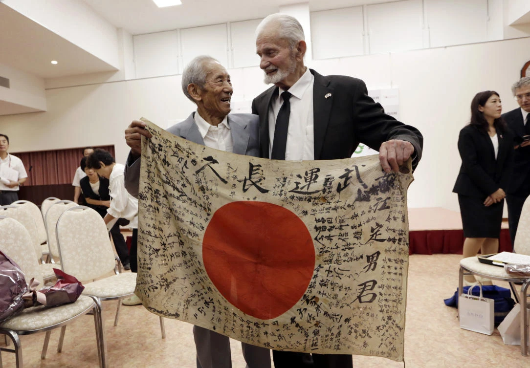 WWII veteran Marvin Strombo, right, and Tatsuya Yasue, 89-year-old farmer, hold a Japanese flag with autographed messages which was owned by his brother Sadao Yasue, who was killed in the Pacific during World Work II, during a ceremony in Higashishirakawa, in central Japan's Gifu prefecture Tuesday, Aug. 15, 2017. Strombo has returned to the fallen soldier's family the calligraphy-covered flag he took from the man's body 73 years ago. (AP)