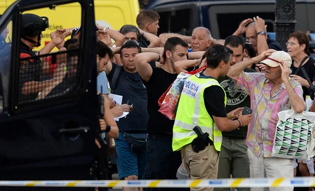 Police officers check the identity of people standing with their hands up near the site of a van attack on the Rambla in Barcelona on Thursday. (AFP / Josep Lago)