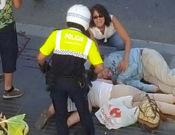 A police officer talks to people attending to injured persons at the scene after a van crashed into pedestrians near the Las Ramblas avenue in central Barcelona, Spain, on Thursday. (REUTERS/Giselle Loots)
