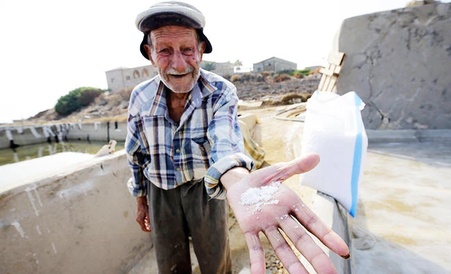 Elias al-Najar, 93, displays salt flakes in the coastal Lebanese town of Anfeh north of the capital Beirut, in this July 21, 2017 photo. (AFP)