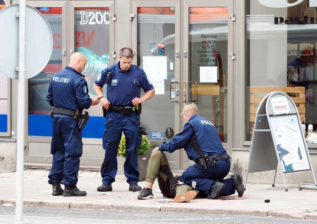 Policemen stand next to an injured person lying on the pavement in the Finnish city of Turku where eight people were stabbed on Friday. (AFP)