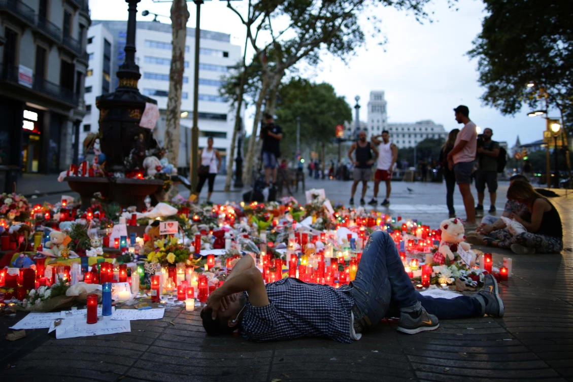 A man lays down next to messages and candles placed after a van attack in central Barcelona, on August 19, 2017. (AP)