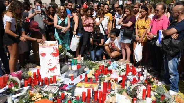People stand next to flowers, candles and other items set up on the Las Ramblas boulevard in Barcelona as they pay tribute to the victims of the Barcelona attack on August 18, 2017. (AFP)