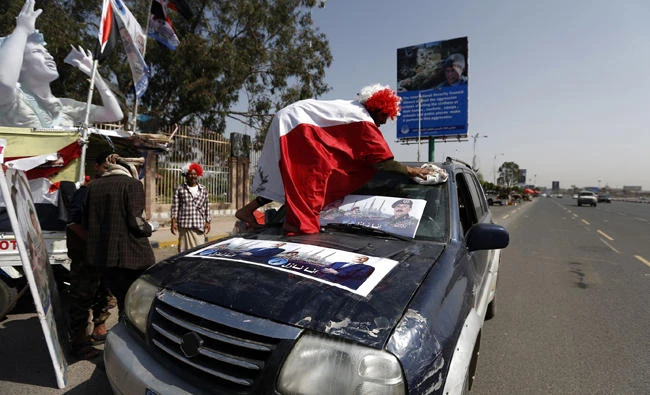 A Yemeni man sticks posters bearing the portrait of former president Ali Abdullah Saleh on his car ahead of celebrations for the 35th year anniversary of the establishment of the former president's party, General People's Congress, in the capital Sanaa on August 19, 2017. (AFP / Mohammed Huwais)