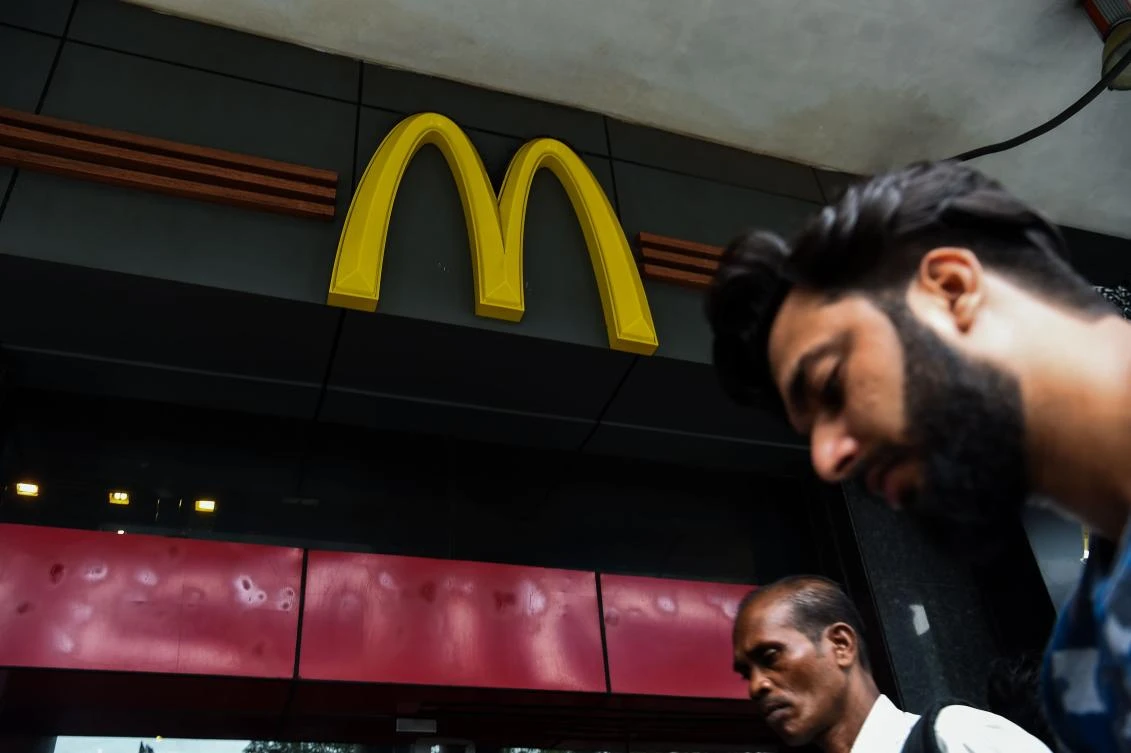 This file photo taken on June 29, 2017 shows Indian men walking past a McDonald's outlet in New Delhi. McDonald's said on August 21 it is shutting 169 restaurants in India after a legal row with a local franchise operator. The fast food chain's Indian subsidiary said it was terminating its agreement with Connaught Plaza Restaurant Ltd (CPRL), alleging breach of contract and payment defaults. (AFP)