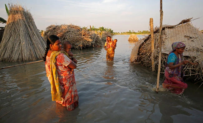 Women carry children as they make their way through a flooded area in Bogra, Bangladesh,on Sunday. (Reuters)