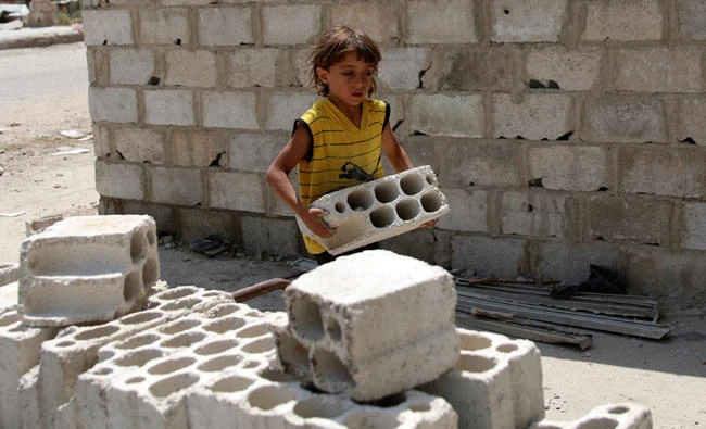 A child holds a brick in the southern Syrian city of Daraa. (Reuters)