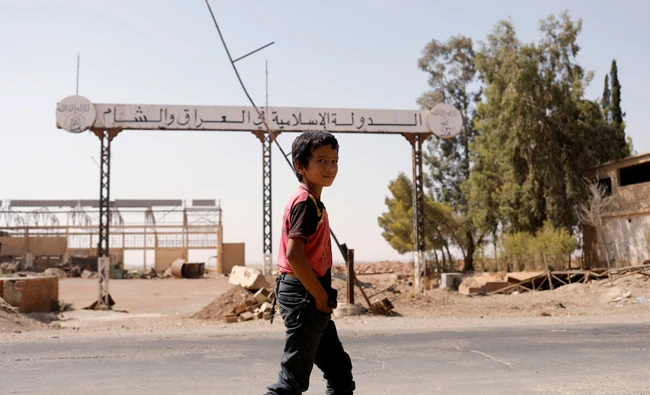 A boy walks past a sign which reads ‘Daesh in Iraq and Syria’ as fighting continues between the Syrian Democratic Forces and Daesh militants in Raqqa, Syria, August 20, 2017. (Reuters)