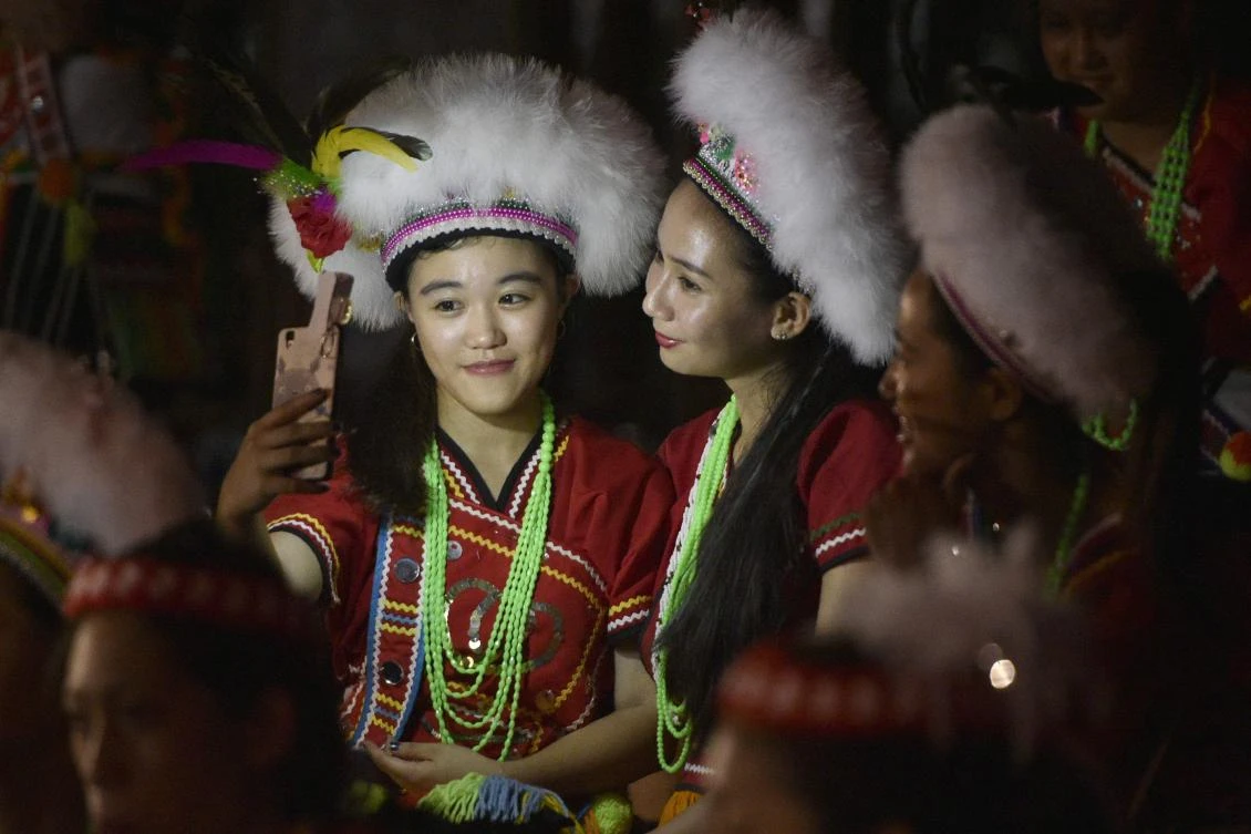 This picture taken on August 19, 2017 shows members of the Amis indigenous group posing for a selfie during the traditional harvest festival in Hualien, eastern Taiwan. As night falls on a square in the village of Matai'an, young women cast critical eyes over a dancing circle of men in embroidered skirts and feathered head dresses as part of an ancient match-making ritual. Known as "Lovers' Night", it is the grand finale of the annual harvest festival for the Amis tribe, the largest of the 16 recognised indigenous groups in Taiwan. (AFP)