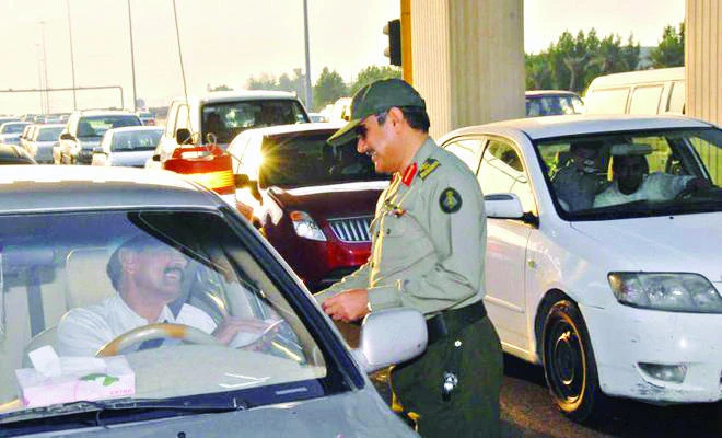 A security officer at a checkpoint along the Makkah-Jeddah Expressway checks the documents of a motorist.