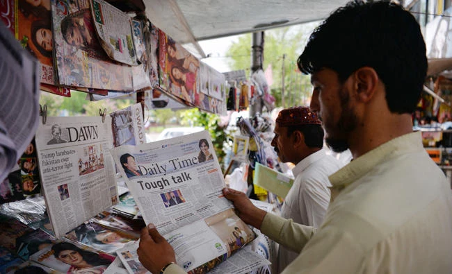 Pakistani residents read newspapers with a front page headline about US President Donald Trump at a stall in Islamabad on Wednesday. (AFP)