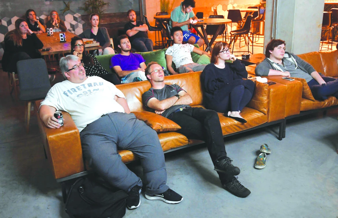 Residents relax in a shared space to watch a televison program on a large screen at The Collective co-living building in west London. (Reuters)