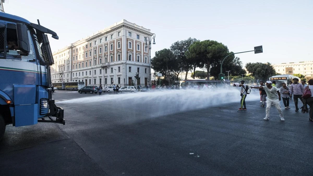 Italian law enforcement officers use water cannons to disperse migrants, in downtown Rome, on Aug 24, 2017. (ANSA via AP)