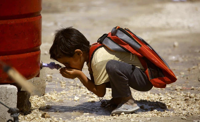 A displaced child from Raqqa drinks water as he heads to attend the first day of the new school year at a refugee camp in Ain Issa on Tuesday. (AFP)