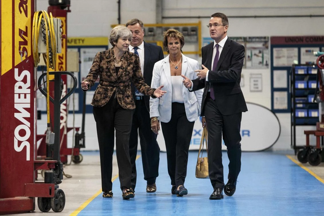 British Prime Minister Theresa May (L) staff as she tours the Alexander Dennis bus and coach manufacturers factory in Guildford, south of London, on August 23, 2017. The company has secured a 44-million GBP government finance deal to sell Britain's famous red double-decker buses to Mexico. A £1.7 billion package of taxpayer-funded support to help businesses make the most of opportunities outside of the European Union has helped 137 firms expand and win overseas contracts over the past year, the prime minister said. (AFP)